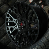 Black alloy wheel with a visible brand logo on a background of tires.