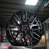 Black alloy wheel on a stand with a blurred indoor background
